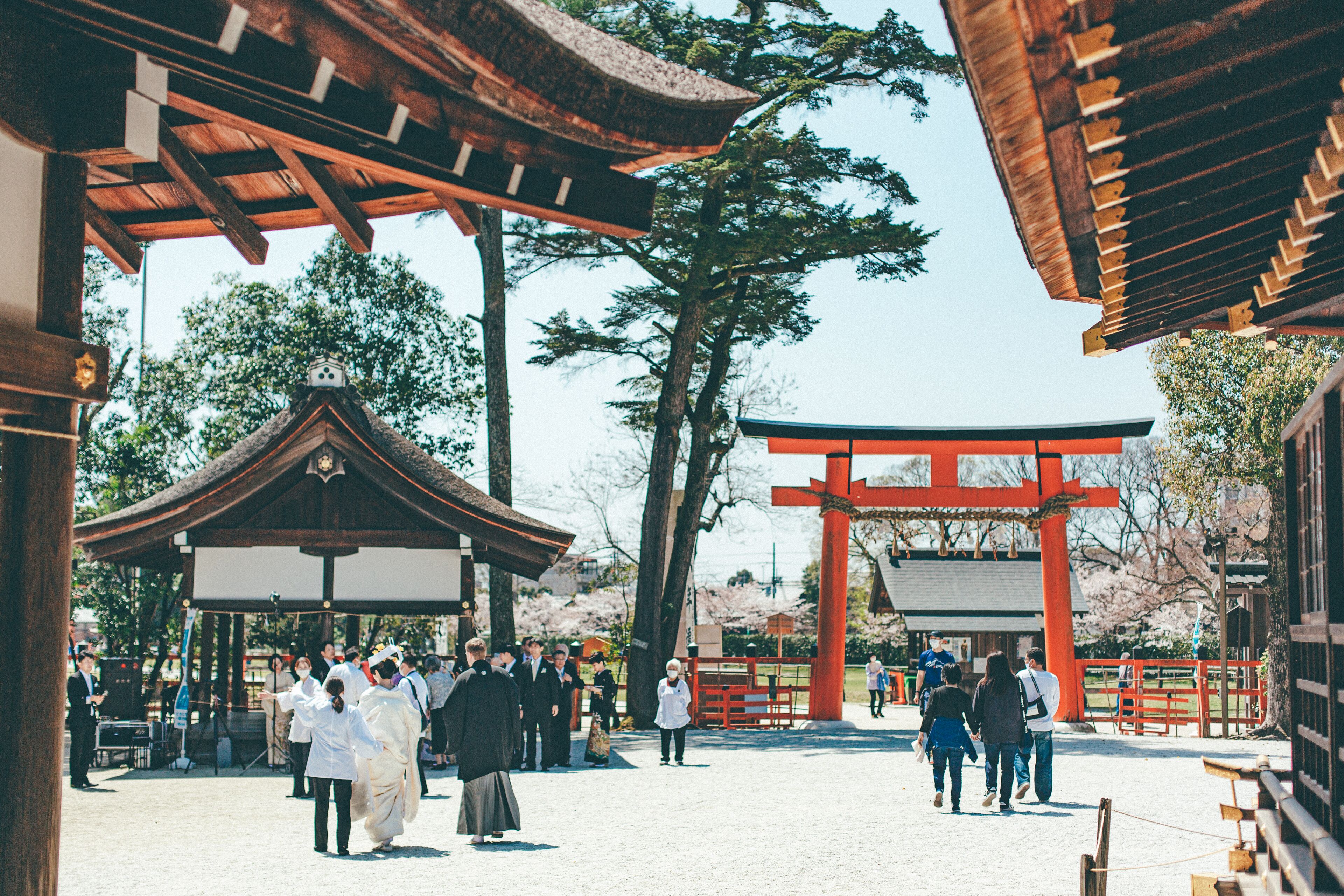 A traditional Japanese gate with a red torii, surrounded by visitors.
