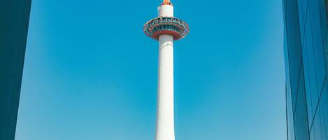 Een hoge witte toren met een rond uitkijkplatform bovenop, tegen een helderblauwe lucht.