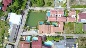 Ett flygbildsbild av ett bostadsområde med flera hus, en swimmingpool och en liten vattenyta.