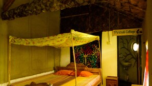 A single bed with a canopy, a small wooden cabinet, and a wall with a tree mural. - Backpackers Eco Village (Gosaba)