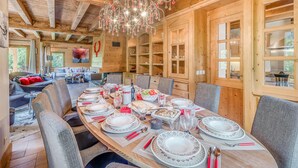 L’intérieur d’un chalet en bois, avec une table à manger dressée pour le repas, entourée de chaises.