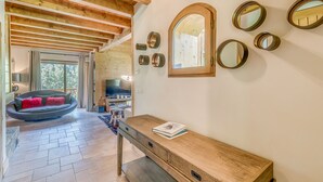 Un intérieur moderne avec un plafond en bois, un coin salon accueillant avec un fauteuil rond, une console en bois et un grand miroir mural.