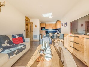 Una sala de estar moderna con sofá, mesa de centro y cocina al fondo.