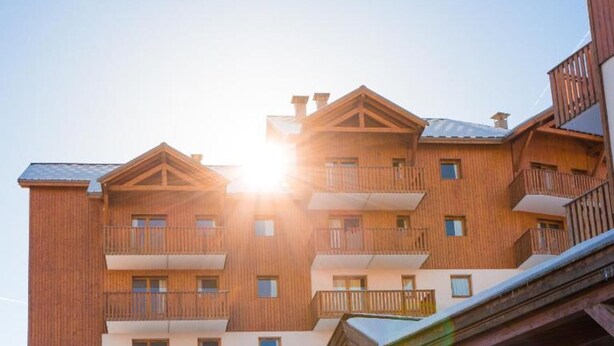 Un edificio de madera de varios pisos con balcones y una pista de esquí.
