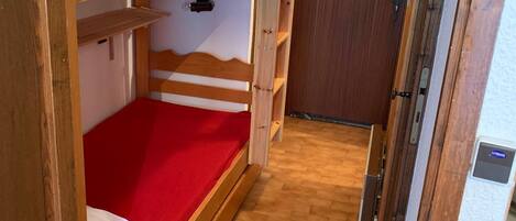 A bunk bed room with a red mattress and wooden headboard.