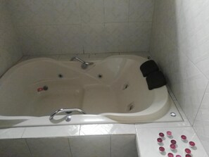A large, freestanding bathtub with a faucet and two drain holes.