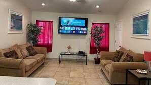 A living room with two sofas, a coffee table, a TV mounted on the wall, and a ceiling fan. - TAMPA FLORIDA VACATION DELIGHT (Tampa)