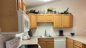 A kitchen with wooden cabinets, a microwave, a stove, a dishwasher, and a coffee maker. - TAMPA FLORIDA VACATION DELIGHT (Tampa)