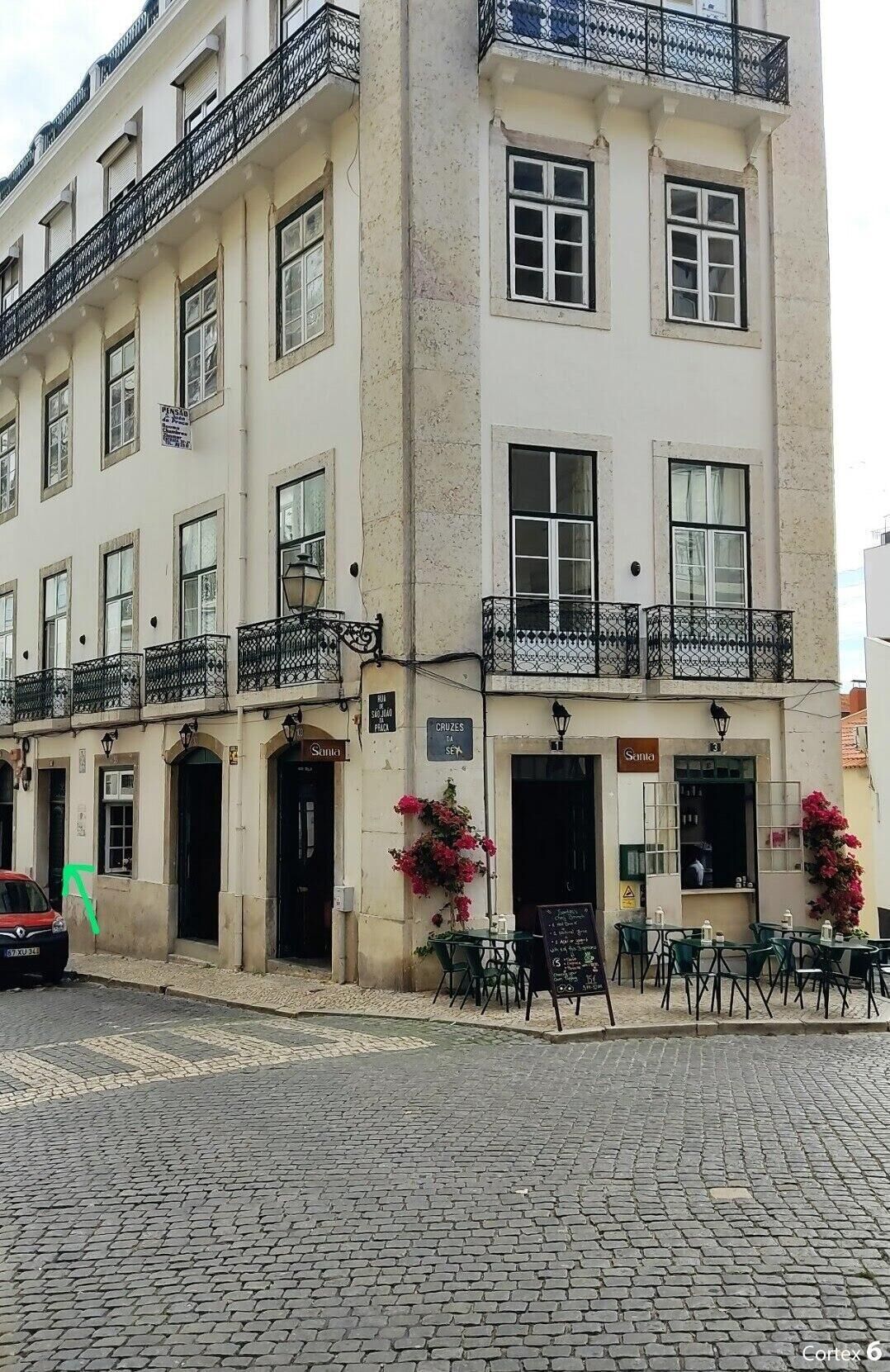 Un edificio de dos pisos con una cafetería en la planta baja llamada 'Santo' y un letrero visible de 'Cruzes SEK'.