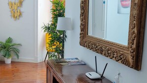 A room with a wooden console table, a mirror with an ornate frame, a lamp, and a potted plant. - No Limit Alfama Guesthouse (Lisbon)