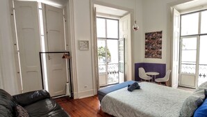 A bedroom with a bed, a sofa, and a dining area with chairs. - No Limit Alfama Guesthouse (Lisbon)