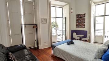 Un dormitorio con una cama, un sofá y una zona de comedor con sillas.