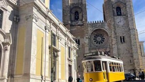 A historic building with a large clock tower and a tram in front. - No Limit Alfama Guesthouse (Lisbon)
