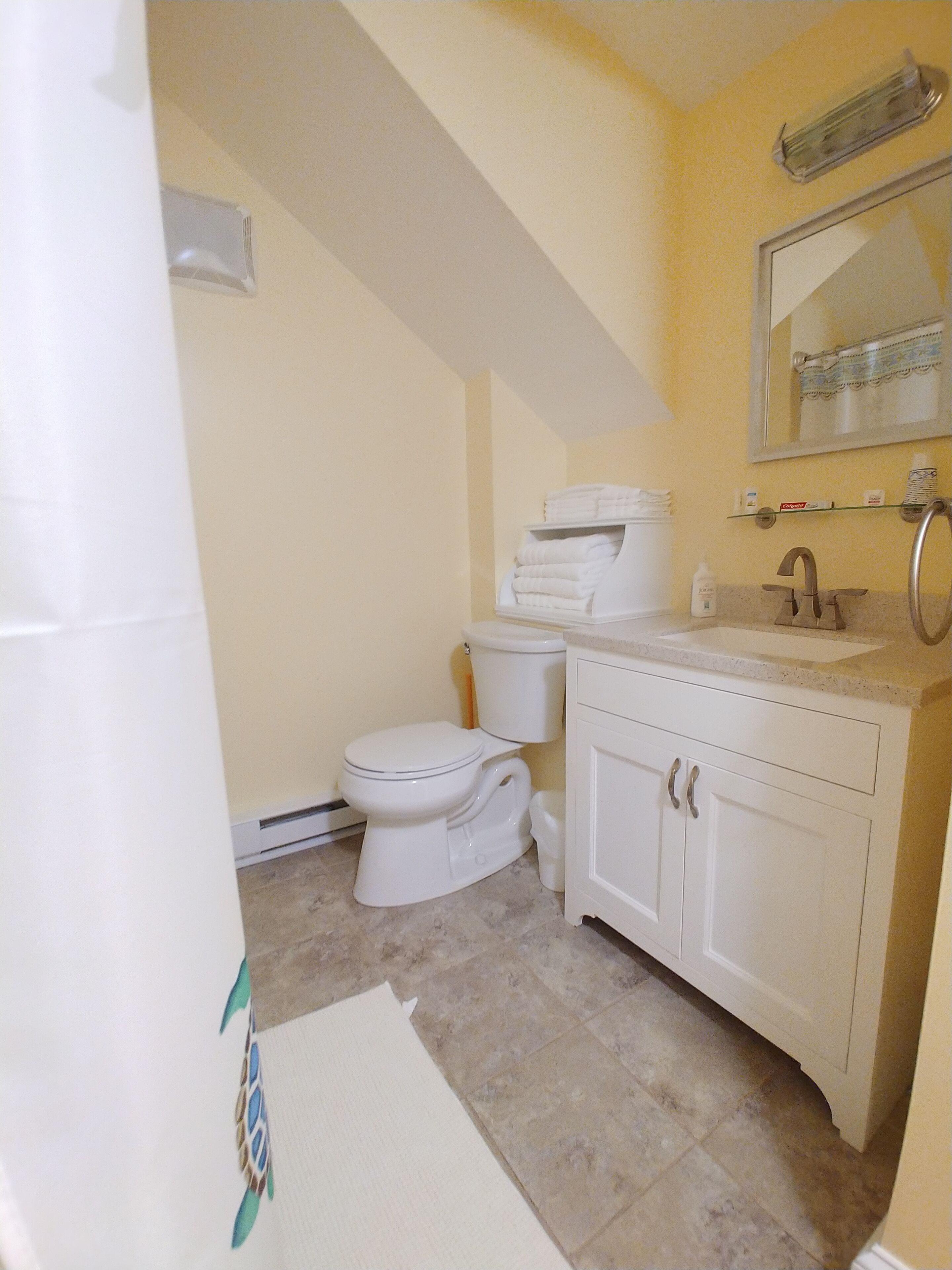 A bathroom with a toilet, sink, and mirror.