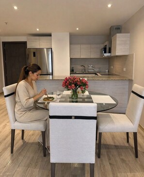 Una cocina moderna con una mesa de comedor, sillas y una persona comiendo.