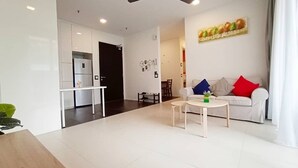 A modern living room with a white sofa, a coffee table, and a dining area with a small table and chairs.