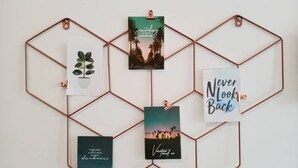 A wall with a geometric metal frame holding four framed pictures.
