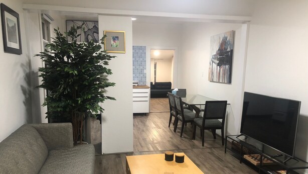 A living room with a sofa, a coffee table, a TV, and a dining area with chairs and a table. - Relaxed and Spacious 2 BR Apartment with a Patio (Oakland)