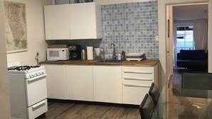 A modern kitchen with white cabinets, a microwave, a stove, and a dining area with a glass table. - Relaxed and Spacious 2 BR Apartment with a Patio (Oakland)