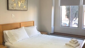 A neatly made bed with white linens, a wooden headboard, and a world map artwork on the wall. - Relaxed and Spacious 2 BR Apartment with a Patio (Oakland)
