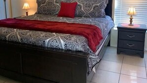 A bedroom with a bed, two bedside tables, and a window with blinds. - Private Oasis Near Disney | Golf Course Home with Private Pool | Pet Friendly (Davenport)