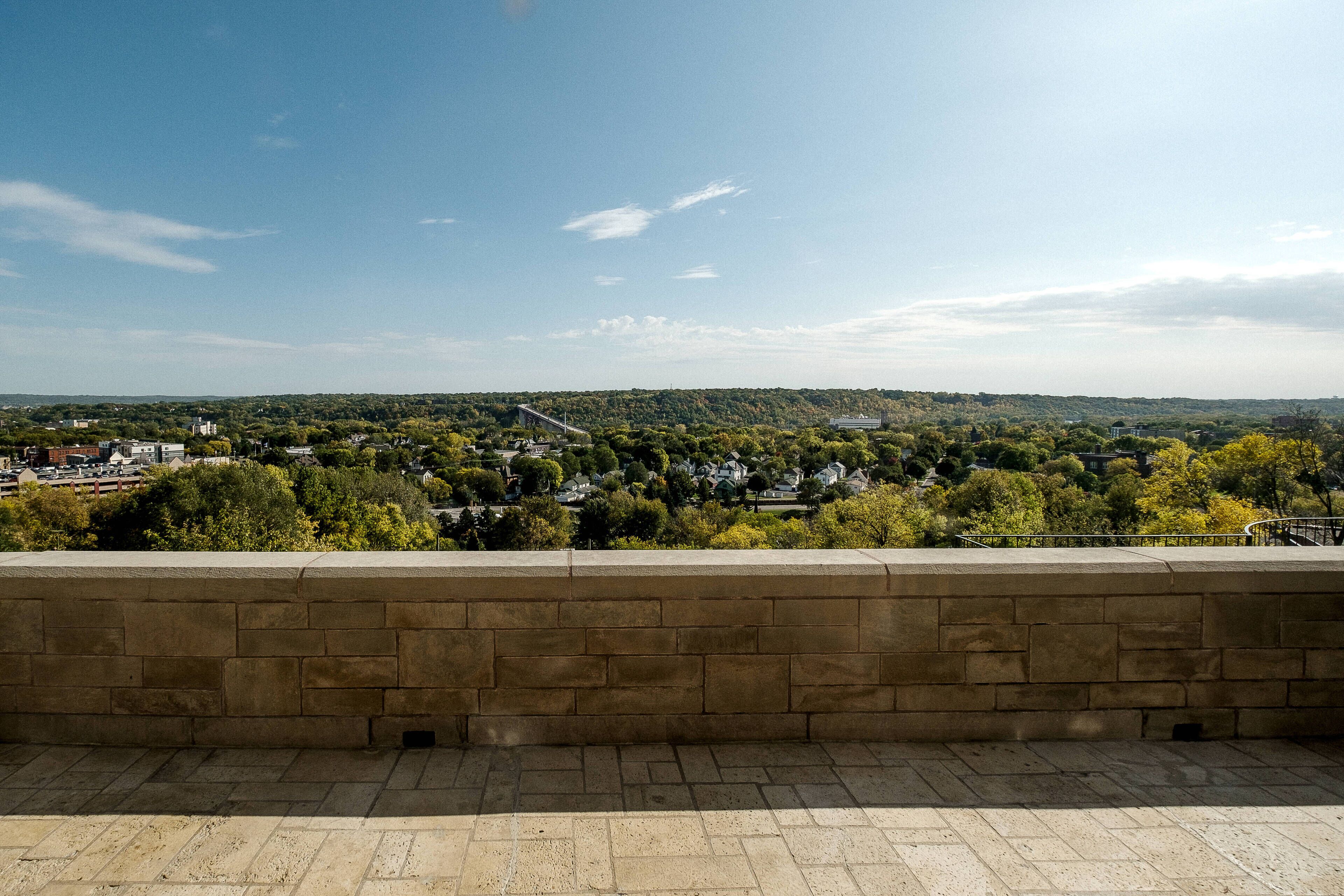 Un mur de pierre surplombe une ville avec ses bâtiments et sa végétation.