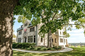 A large, historic building with a prominent American flag, surrounded by mature trees and a well-maintained lawn. - The Davidson (St. Paul)