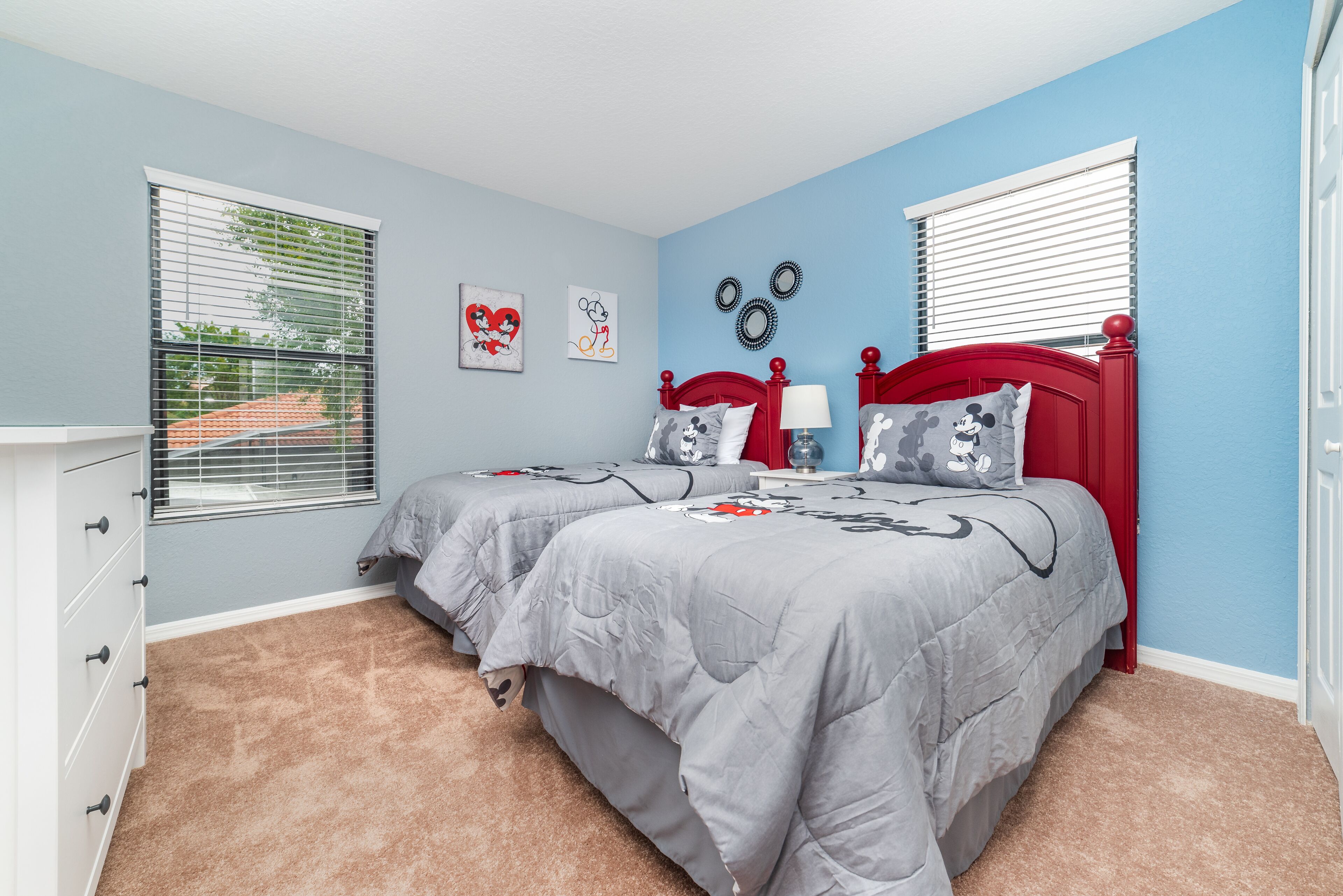 A bedroom with two beds, a dresser, and a window with blinds.