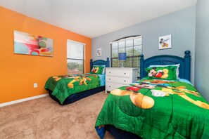 A bedroom with two beds, each covered with green bedding featuring cartoon characters. There is a white dresser, a window with blinds, and a colorful abstract painting on the wall. - ✨ Luxurious 5BR Villa w/ Private Pool & Game Room near Disney 🏝️🎢 (Clermont)