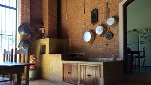 Une cuisine rustique avec un mur en briques, des armoires en bois et des ustensiles de cuisine suspendus.