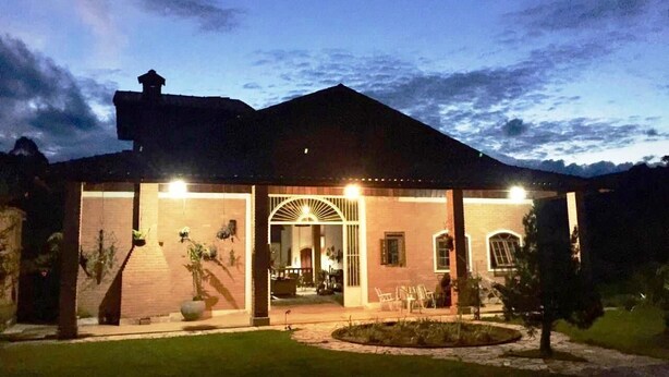 Une maison à deux étages dotée d’un patio couvert, d’une entrée principale et d’un petit jardin.