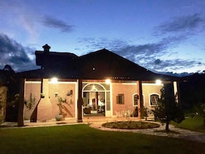 A two-story house with a covered patio area, a front entrance, and a small garden.