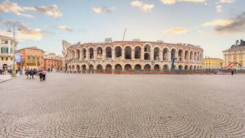 Un antico anfiteatro con una piazza lastricata di fronte.