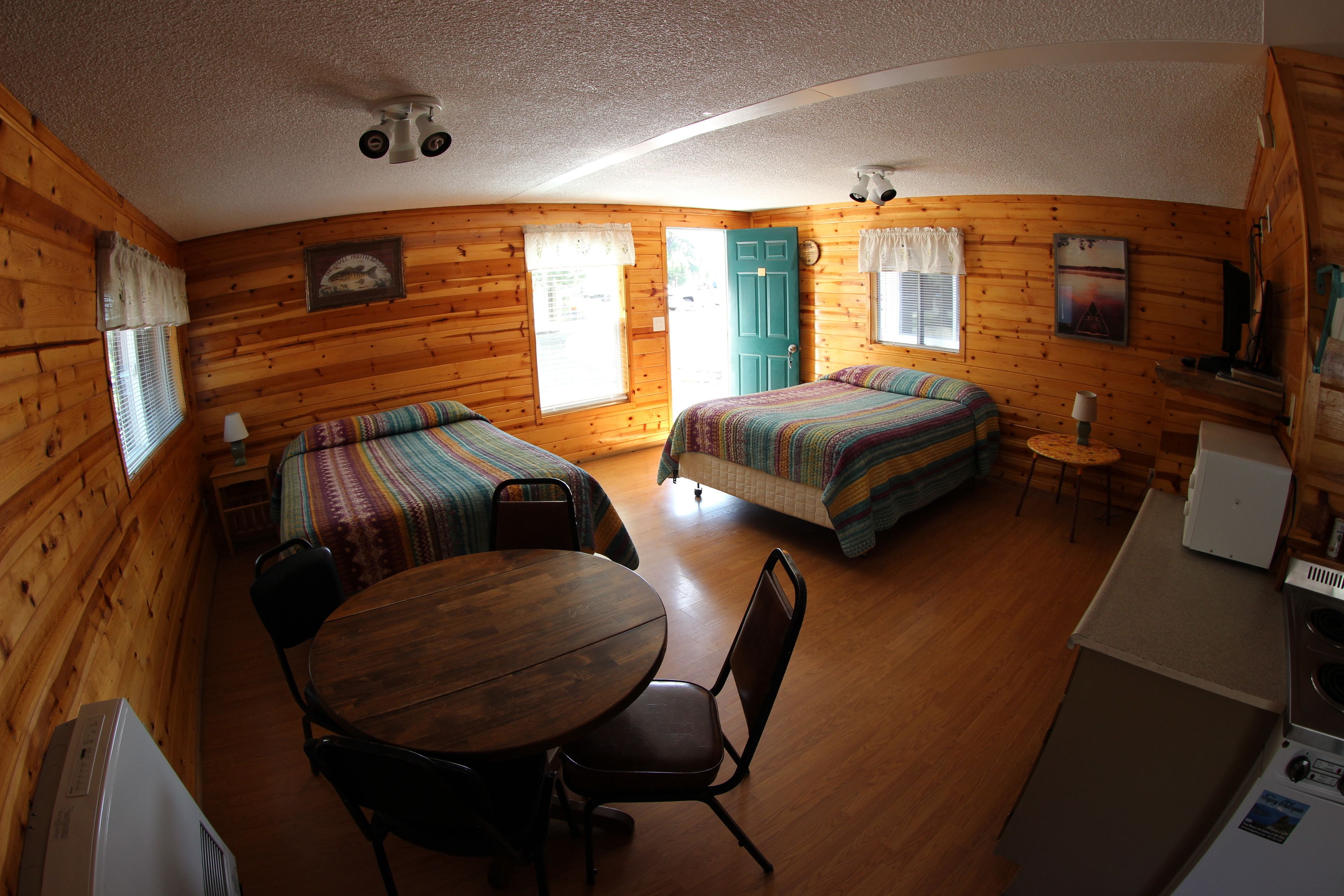 Une cabine équipée de deux lits, d’une table à manger, de chaises, d’un coin cuisine et d’un ventilateur de plafond.