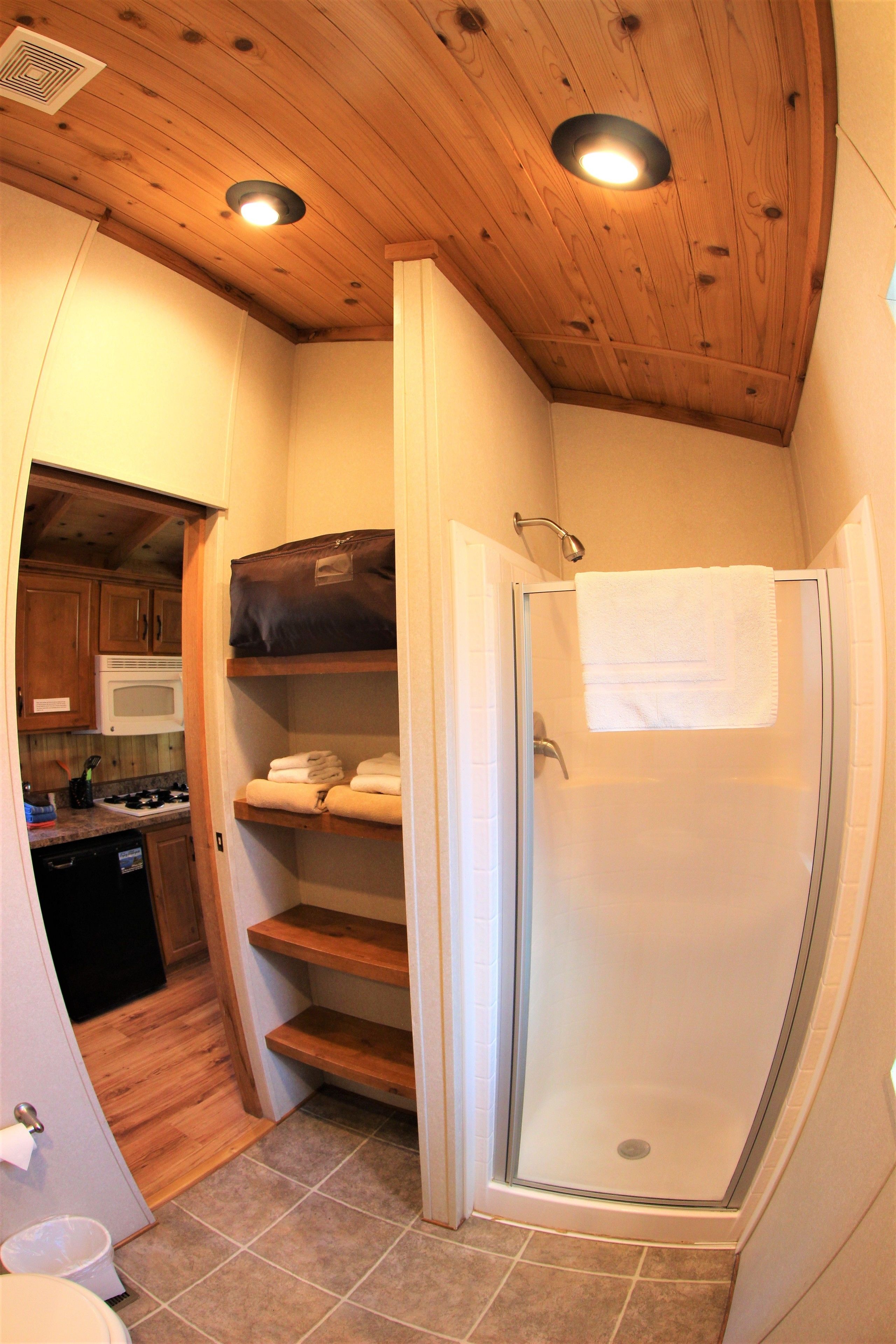 A compact bathroom with a shower, toilet, and a small kitchen area.