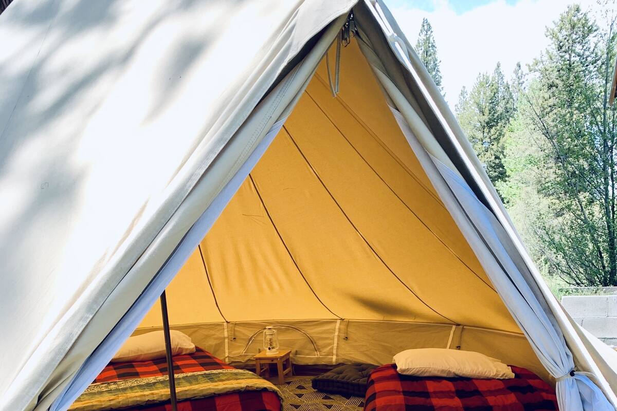 A tent with two beds, a small table, and a rug.