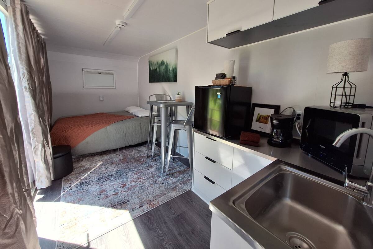A compact kitchenette with a refrigerator, microwave, and sink.
