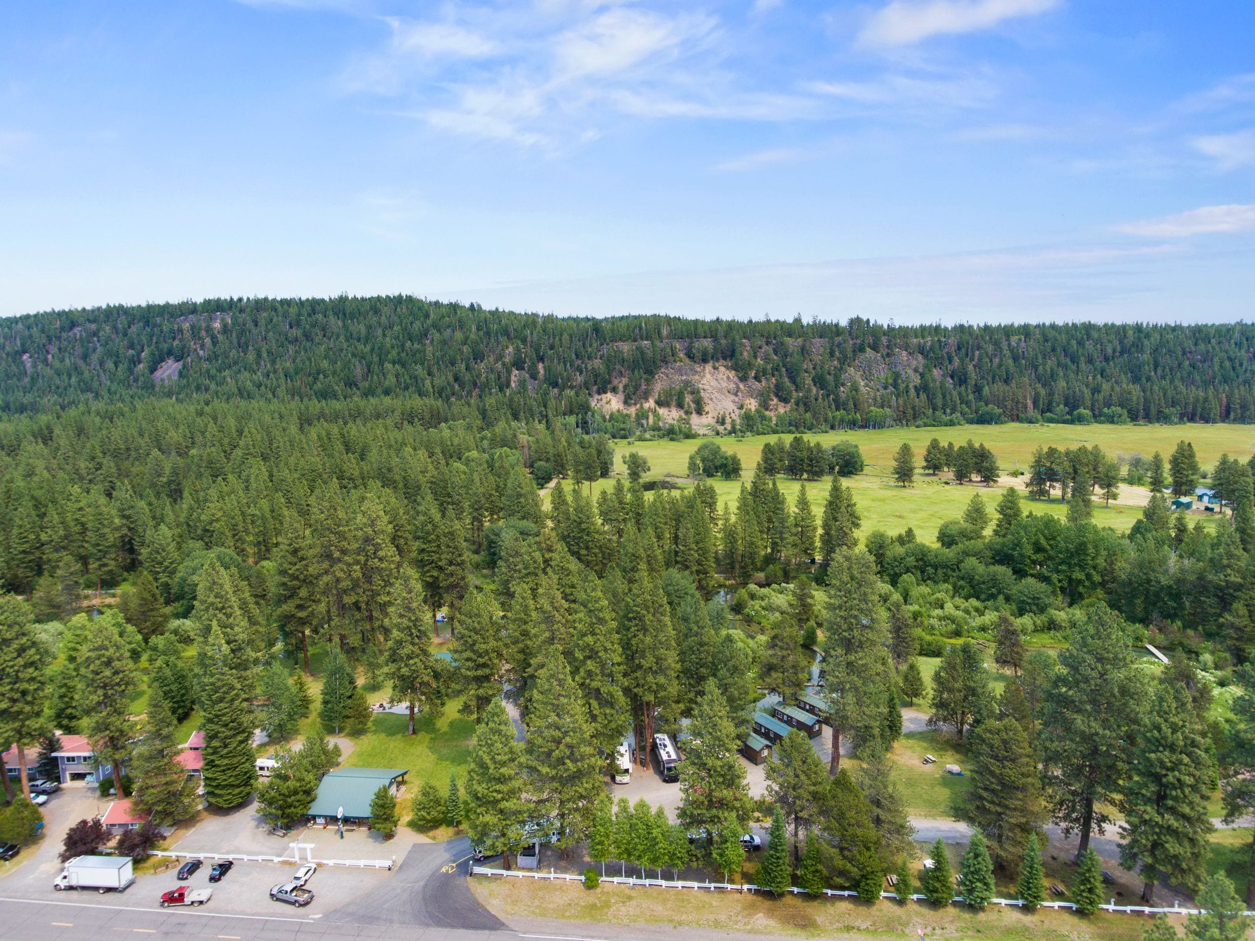Un chalet doté de plusieurs cabanes, d’un espace de stationnement et entouré d’un paysage boisé.