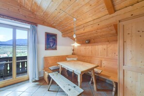 Un intérieur en bois avec une table et des bancs, un ventilateur de plafond et une vue par la fenêtre.