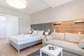 Una habitación de hotel moderna con una cama, un sofá, una mesita y una pizarra blanca.