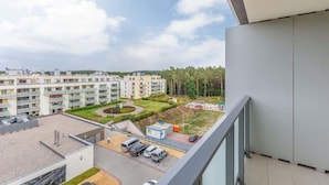 Un edificio residencial con varios balcones, zona de estacionamiento y un patio ajardinado.