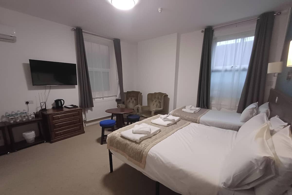 Hotellihuone, jossa on kaksi sänkyä, televisio, työpöytä ja tuoli.