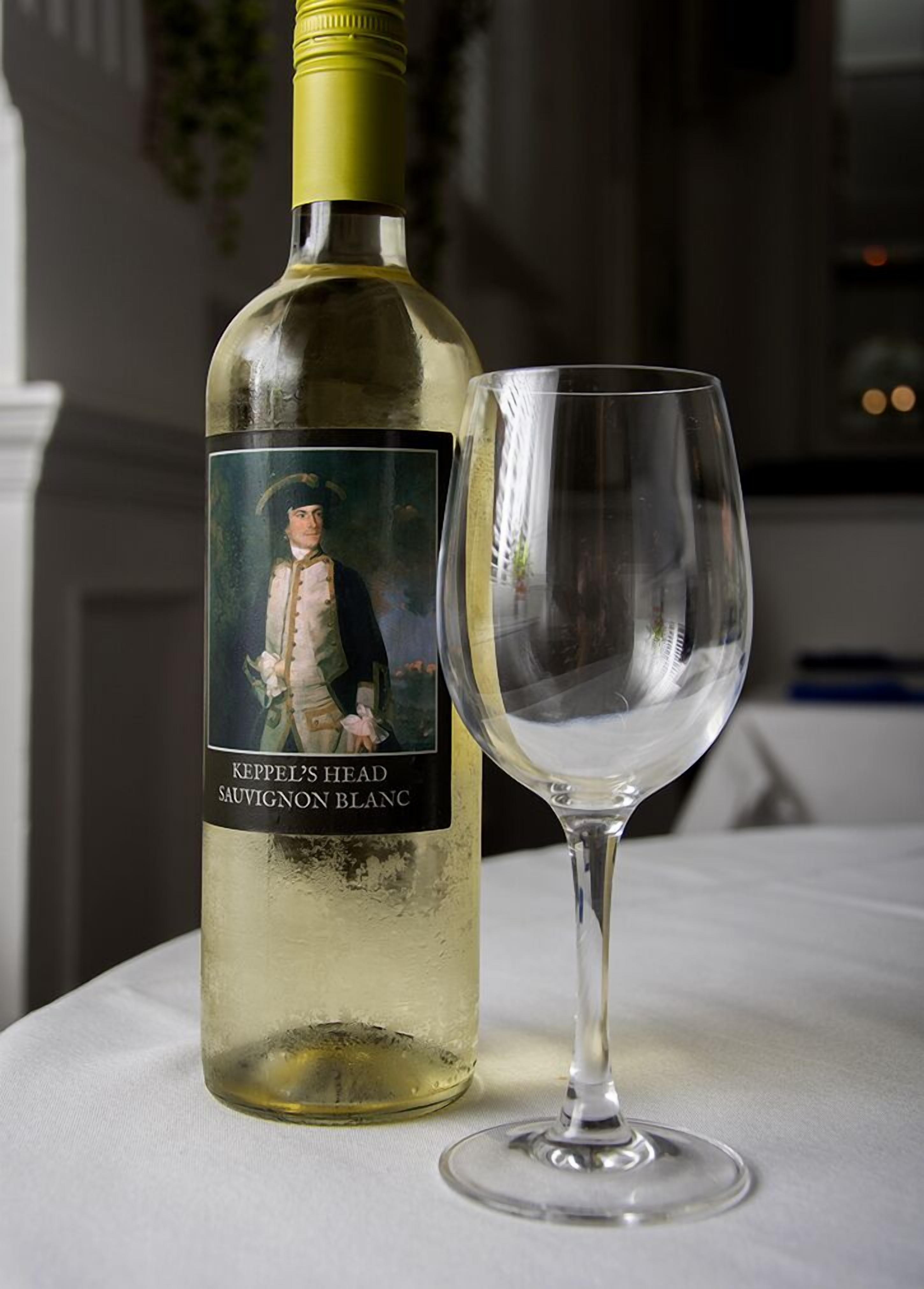 A bottle of Keppel's Head Sauvignon Blanc next to an empty wine glass on a table.