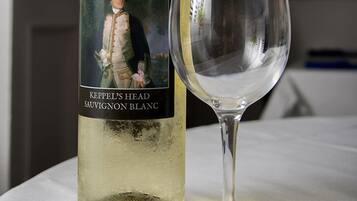 A bottle of Keppel's Head Sauvignon Blanc next to an empty wine glass on a table.