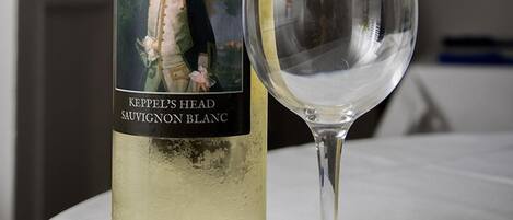 A bottle of Keppel's Head Sauvignon Blanc next to an empty wine glass on a table.