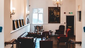 Eine geräumige Lobby mit hoher Decke, einem Chandelier, einem Kamin und einem großen Gemälde an der Wand.