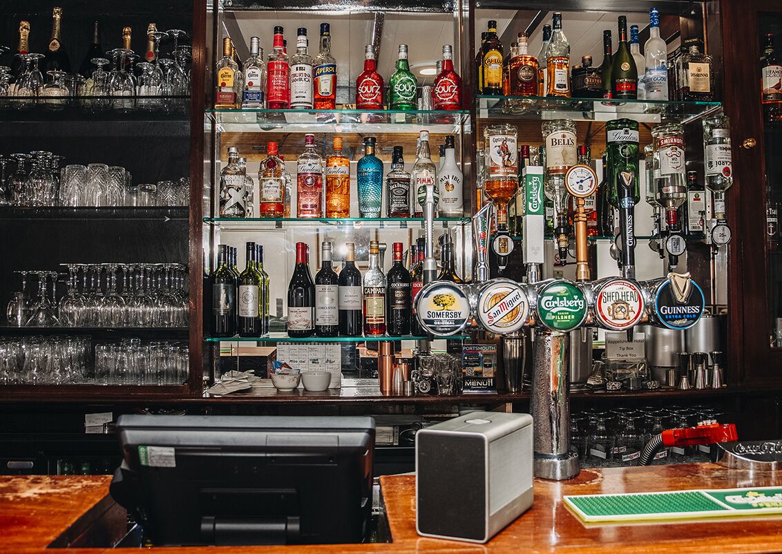 Un espace bar avec un assortiment de bouteilles d’alcool et un système de distribution en fût.
