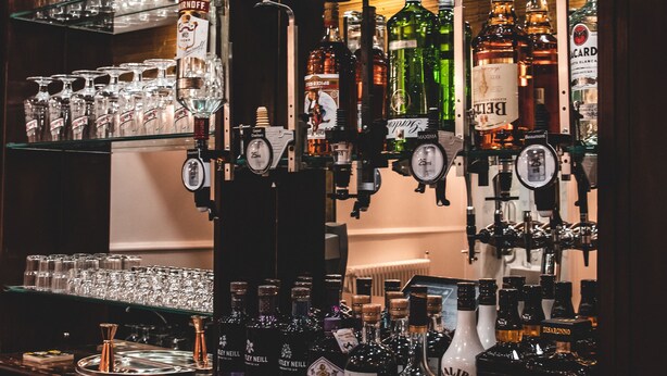 Eine Bar mit Regalen voller verschiedener Spirituosenflaschen und Gläser.