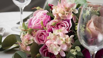 A table setting with a bouquet of pink and white flowers, a wine glass, and a spoon.