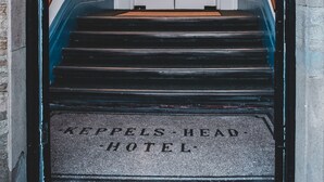 Eine Treppe führt zu einem Hotel Eingang, darüber hängt ein Kronleuchter.